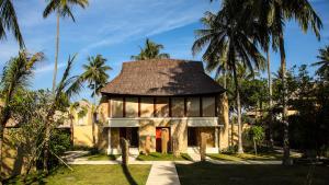 a house with a thatched roof and palm trees at Qunci Villas Resort in Senggigi