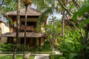 a house with a balcony in the middle of trees at Qunci Villas Resort in Senggigi