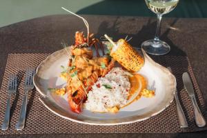 a plate of food with shrimp and rice and a glass of wine at Qunci Villas Resort in Senggigi