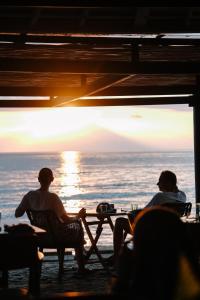 two men sitting at a table on the beach at Qunci Villas Resort in Senggigi