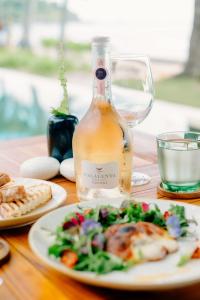 a table with a bottle of wine and a plate of food at Qunci Villas Resort in Senggigi