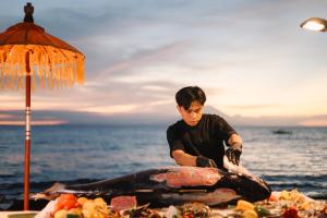 a young boy preparing a fish on the beach at Qunci Villas Resort in Senggigi