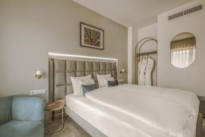 ein Schlafzimmer mit einem großen weißen Bett und einem Stuhl in der Unterkunft Hotel Essence in Pogány