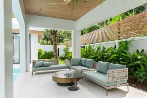an outdoor patio with two couches and a table at Mouana Breeze Mai Khao 4-bedroom Pool Villa 9919 in Mai Khao Beach