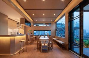 a restaurant with a table and chairs and large windows at 隐栖堂酒店 成都太古里合江亭店 in Chengdu
