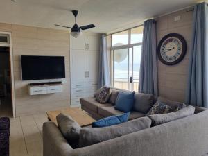 a living room with a couch and a clock on the wall at Albatros 506 in Amanzimtoti