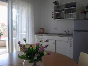 a kitchen with a table with a vase of flowers on it at Apartments MiaMaja in Novalja