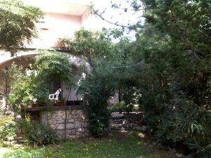 a house with a stone wall and trees in a yard at Apartments MiaMaja in Novalja