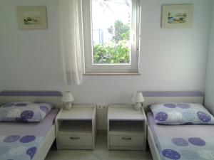 two beds in a room with a window at Apartments MiaMaja in Novalja