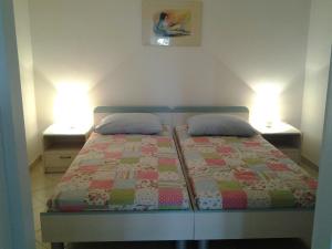 a bedroom with a bed with two nightstands and two lamps at Apartments MiaMaja in Novalja