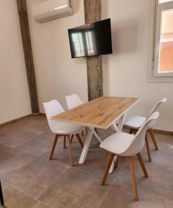 a wooden table with white chairs and a television on a wall at Espectacular Estudio muy grande in Valdemoro