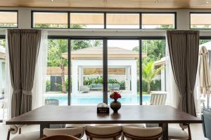 a dining room with a large window and a table at Mouana Breeze Mai Khao 4-bedroom Pool Villa 9919 in Mai Khao Beach