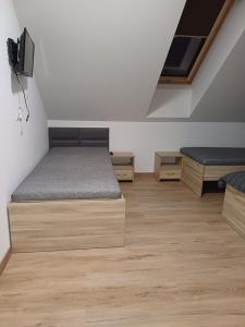 a room with two beds and a tv on the wall at Noclegi u Wilka in Chorzelów
