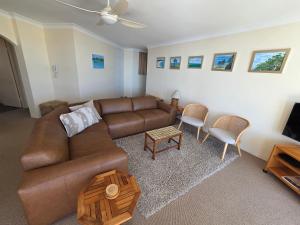 a living room with a brown leather couch and chairs at Beachpoint, 401 in Forster