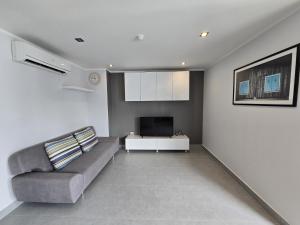 a living room with a couch and a tv at Sleek Corner 1 Bed Apt T1-607 in Chalong 