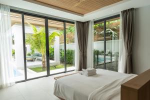a bedroom with a bed and large glass windows at Mouana Breeze Mai Khao 4-bedroom Pool Villa 9919 in Mai Khao Beach +67 photos