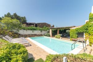 a swimming pool in a yard with bushes and trees at Villa Ginepro con Piscina Privata in San Teodoro
