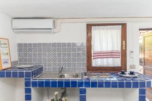 a blue tiled kitchen with a sink and a window at Villa Ginepro con Piscina Privata in San Teodoro +25 photos