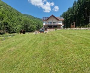a house on a hill with a large grass field at Pensiunea Poiana Țibleș in Suplai