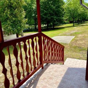 a wooden railing on a porch with a view of a park at Apartmanház - Delta Kemping in Balatonederics