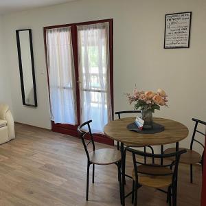a dining room with a table with a vase of flowers at Apartmanház - Delta Kemping in Balatonederics