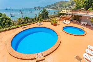 a view of two swimming pools with chairs and the ocean at Giulia's Apartment on the sea in Taormina