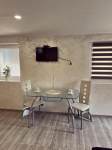 a dining room with a glass table and chairs at La Perla Apartman 1 in Bela Crkva +4 photos