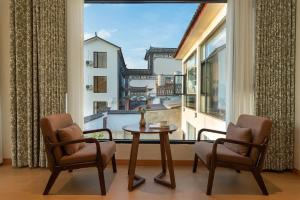 大理古镇Dali Blue House Sea View B&B的一间有一张桌子、两把椅子和一扇大窗户的房间