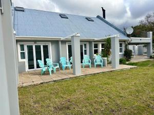 a house with blue chairs on a patio at Myrtle 3 Bed House in Tokai