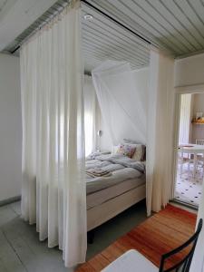 a bed with white curtains in a room at Väentupa in Kaarina