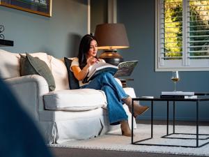 a woman sitting on a couch reading a book at Kaitahi Lodge in Palmerston North