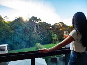 a woman standing on a balcony with a glass of wine at Kaitahi Lodge in Palmerston North