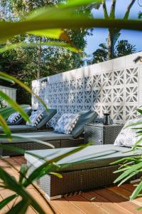 a bench with pillows sitting on a wooden deck at The Cottage at Pearl Beach in Pearl Beach