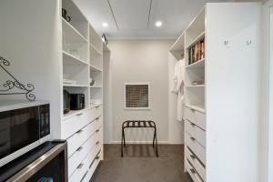 a walk in closet with white cabinets and a chair at Kaitahi Lodge in Palmerston North