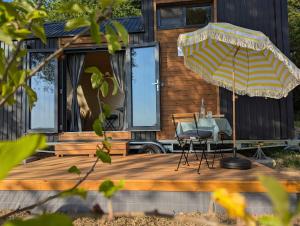 una terrazza in legno con tavolo e ombrellone di La Vue en Rose by Tiny Away a Sénaillac-Latronquière