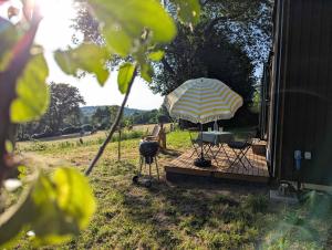 un patio con un ombrellone, due sedie e una griglia di La Vue en Rose by Tiny Away a Sénaillac-Latronquière