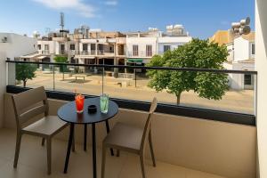 a balcony with a table and chairs and a view of a city at NÓA Rooms - Adults Only in Ayia Napa