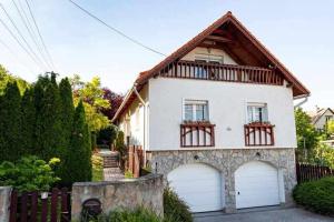 a large white house with two garage doors at Vitorlás Vendégház Balatonalmádi in Balatonalmádi