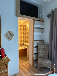 a bathroom with a tv on the wall and a chair at Chambre Bohème chic avec jacuzzi in Liouc
