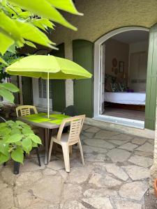 a table with a green umbrella on a patio at Chambre Bohème chic avec jacuzzi in Liouc