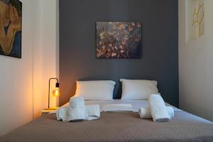 1 cama con almohadas blancas y una pintura en la pared en Eclectic Urban Nest, en Heraklion
