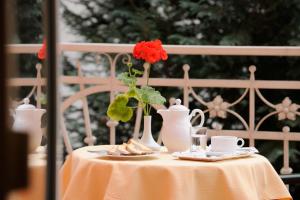 einen Tisch mit einer Vase mit einer roten Blume darauf in der Unterkunft Hotel Scherer in Salzburg
