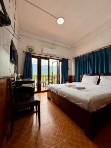 a bedroom with a bed and a desk and a window at Domon Riverside Hotel in Vang Vieng