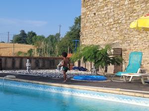un ragazzo in piedi accanto alla piscina di Relais de la poste rez-de-chaussée a Monclar-de-Quercy