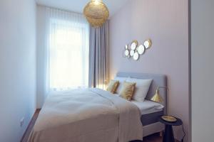a white bedroom with a bed and a window at LeonArt Living 21 in Graz