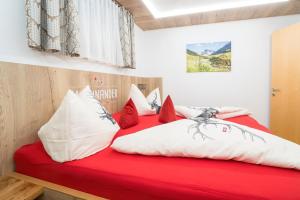een rood bed met witte en rode kussens erop bij Haus Barbara in Sankt Gallenkirch