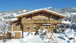 a large wooden building with snow on the ground at Appartement Bergrose in Hopfgarten im Brixental