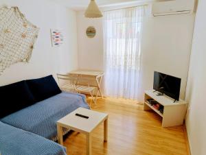 a living room with a blue couch and a tv at Gospoja Park & Beach Apartment Vrbnik in Vrbnik