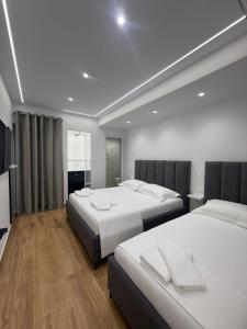 a hotel room with two beds with white sheets at Hotel Barjami in Sarandë +37 photos