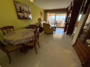 a dining room with a table and chairs and a living room at Penthouse w/ sea view, pool & beach in Calafell